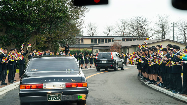 Students and staff smiling and waving Tibetan flags welcome His Holiness on his arrival at Reitaku University in Chiba, Japan on November 19, 2018. Photo by Tenzin Choejor